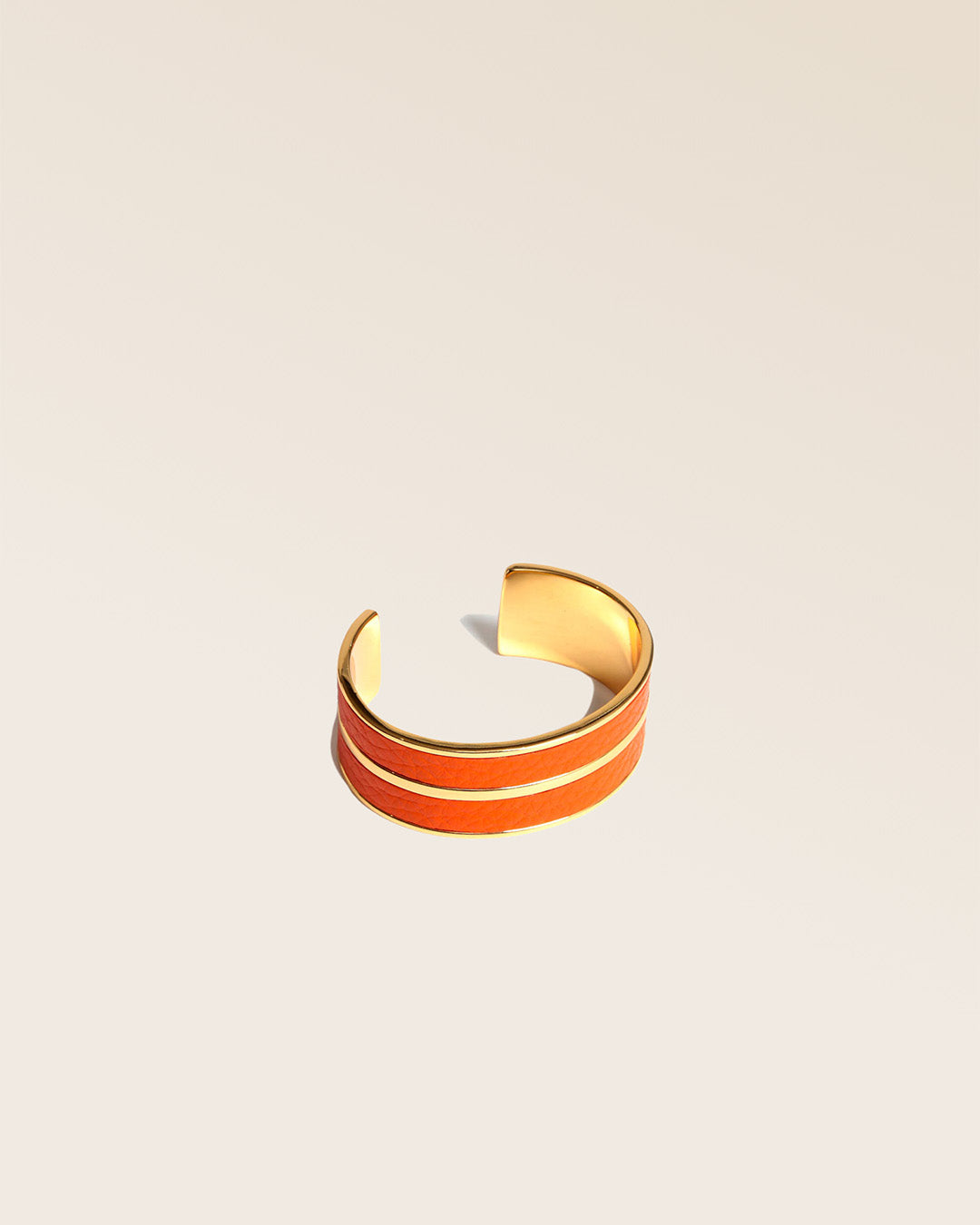 Notre bracelet Adeline Renouard en cuir façon vigogne orange, vu de quart en studio.