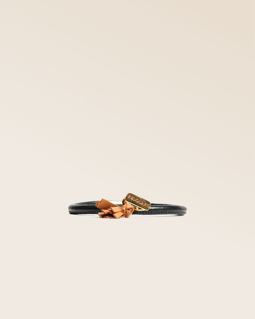 Notre bracelet Jumping en cuir d'agneau noir et pompon camel vu de face en studio.