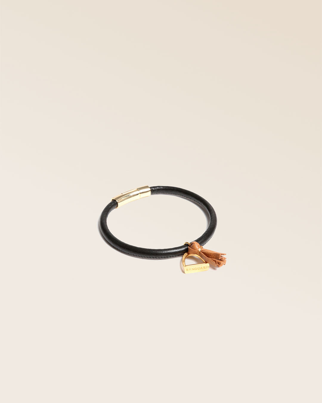 Notre bracelet Jumping en cuir d'agneau noir et pompon camel vu de quart en studio.