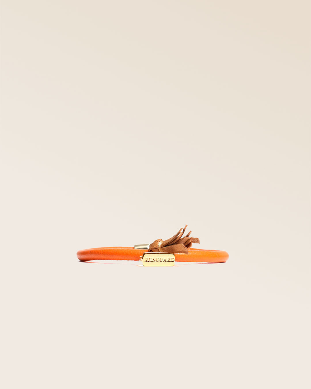 Notre bracelet Jumping Renouard en cuir d'agneau orange et pompon camel, vu de face en studio.