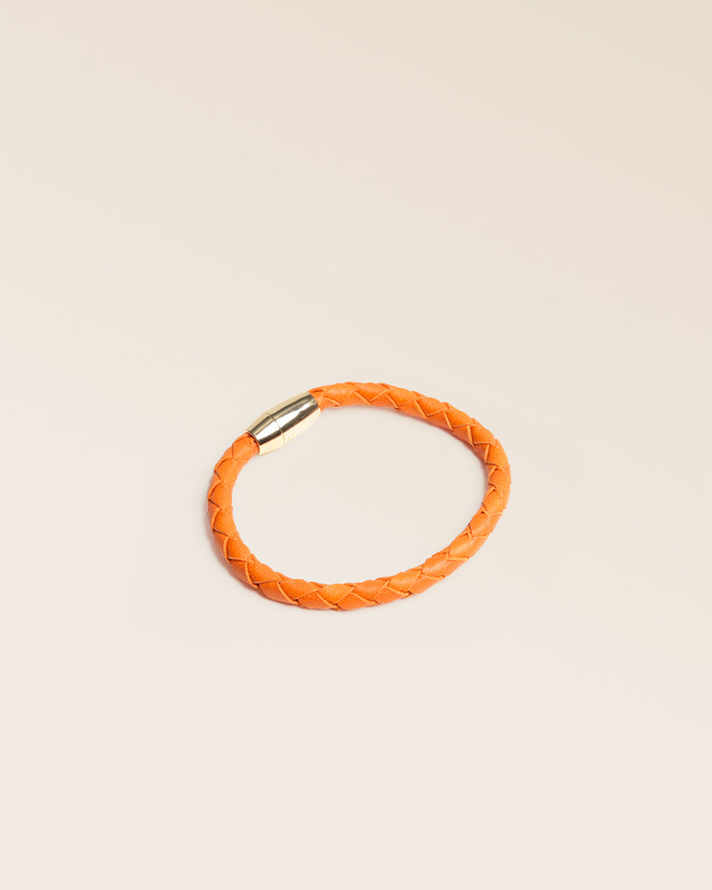 Notre bracelet Mohican en cuir d'agneau tressé orange vu de quart en studio.