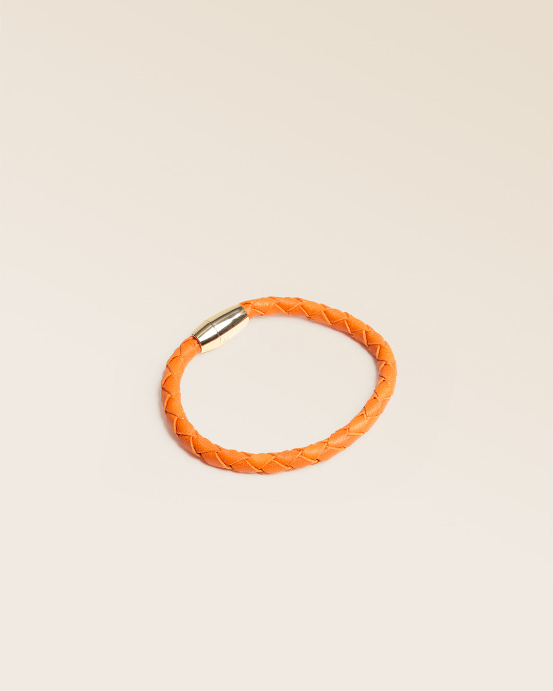 Notre bracelet Mohican en cuir d'agneau tressé orange vu de quart en studio.
