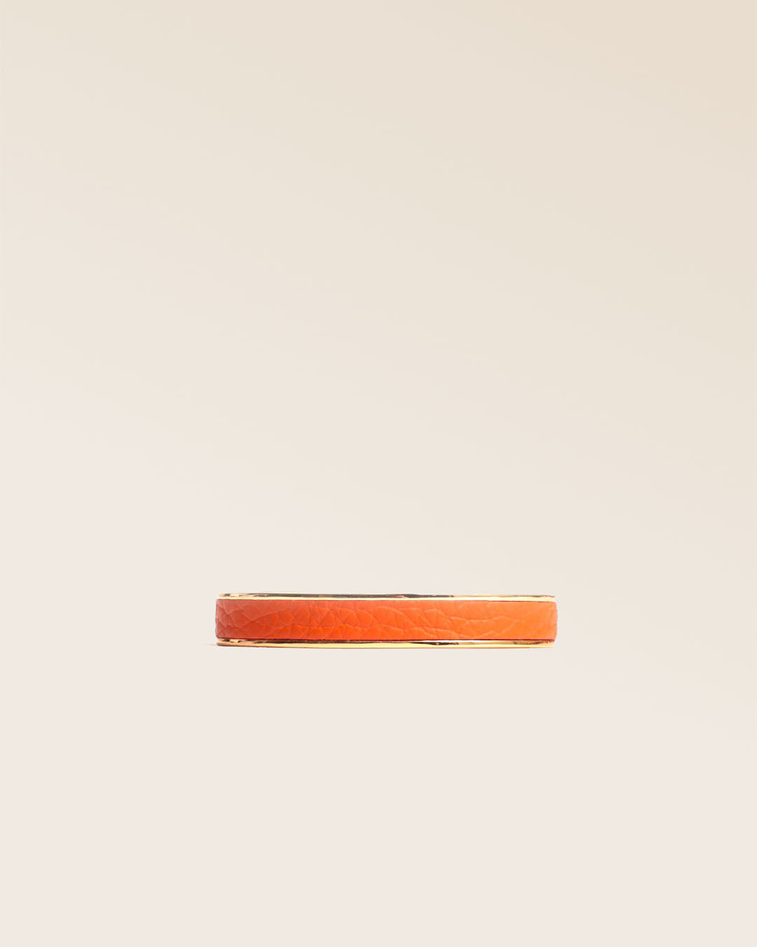 Our golden Pacôme bracelet in orange vicuña-style leather, seen from the front in the studio.