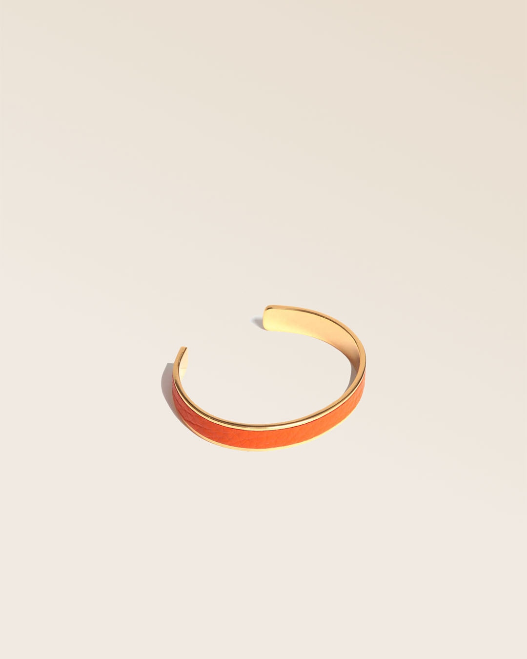 Our golden Pacôme bracelet in orange vicuña-style leather, seen from the quarter in the studio.