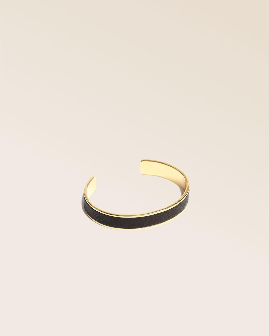 Our Pacôme Renouard bracelet in gilded metalwork and smooth black leather, seen from the quarter in the studio.