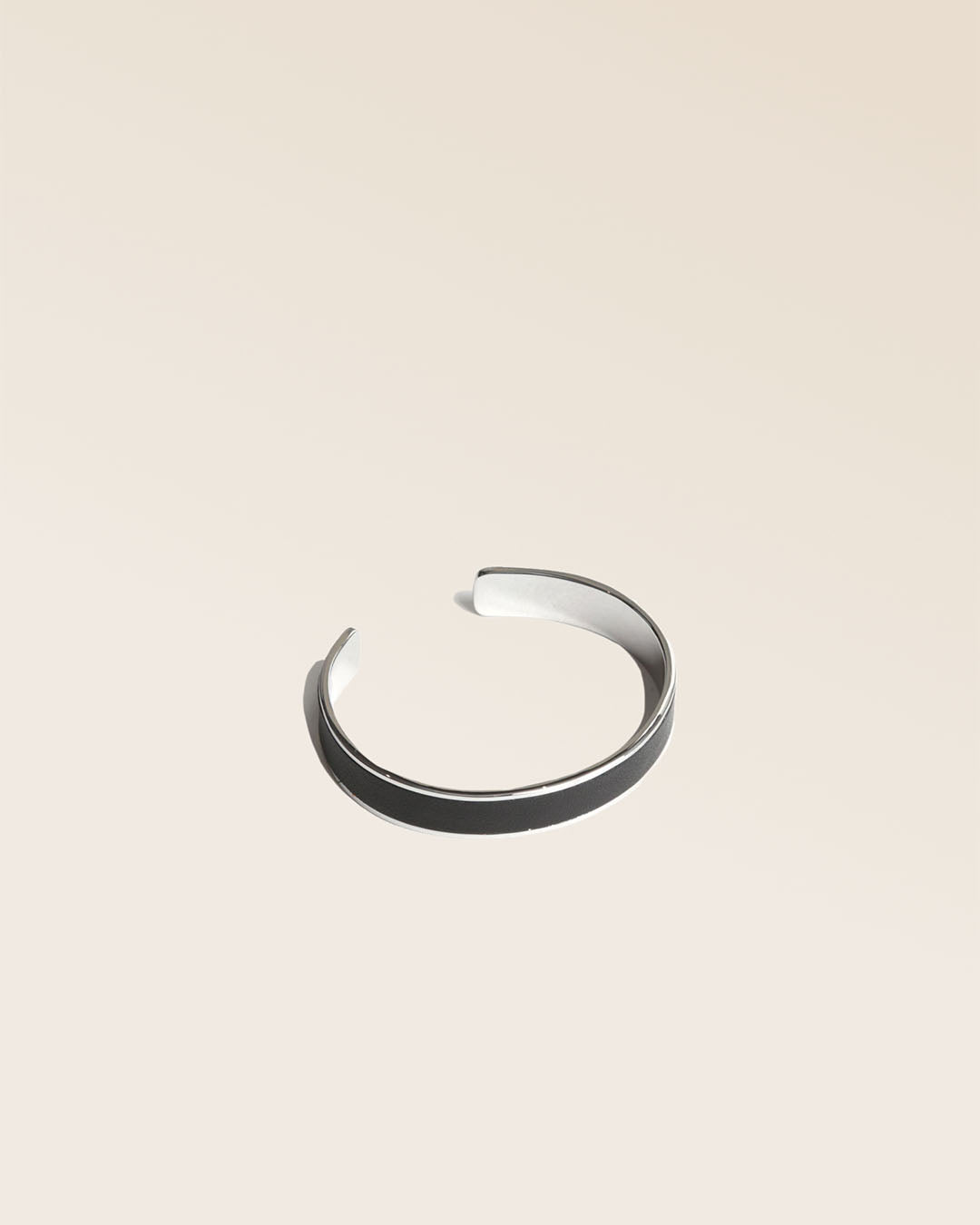 Our Pacôme Renouard bracelet in nickel-plated metal and smooth black leather, seen from the quarter in the studio.