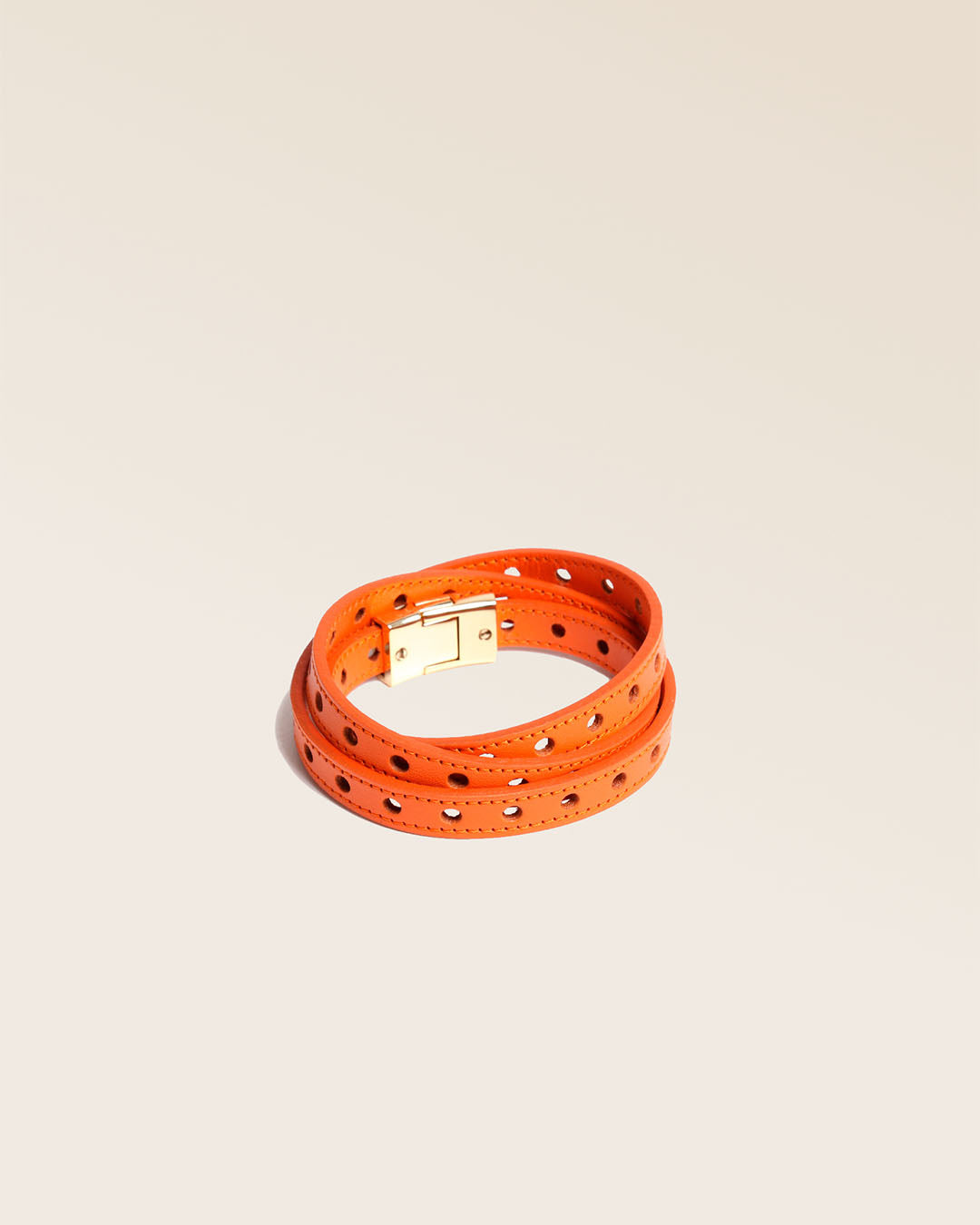 Our Totem bracelet in orange perforated lambskin seen from the quarter in the studio.