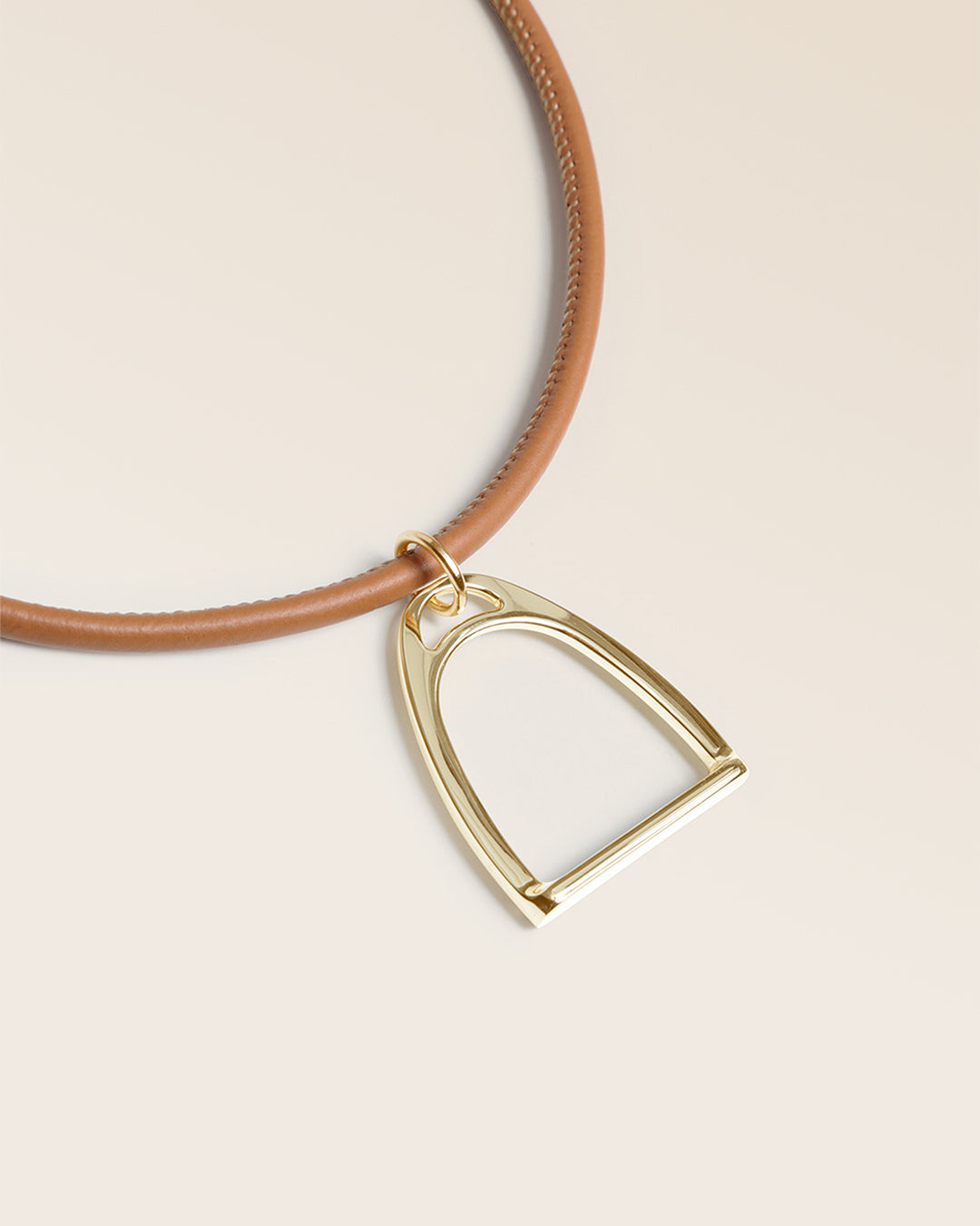 Notre collier Attelage Renouard, en cuir d'agneau camel et accessoire doré, vu de près en studio.