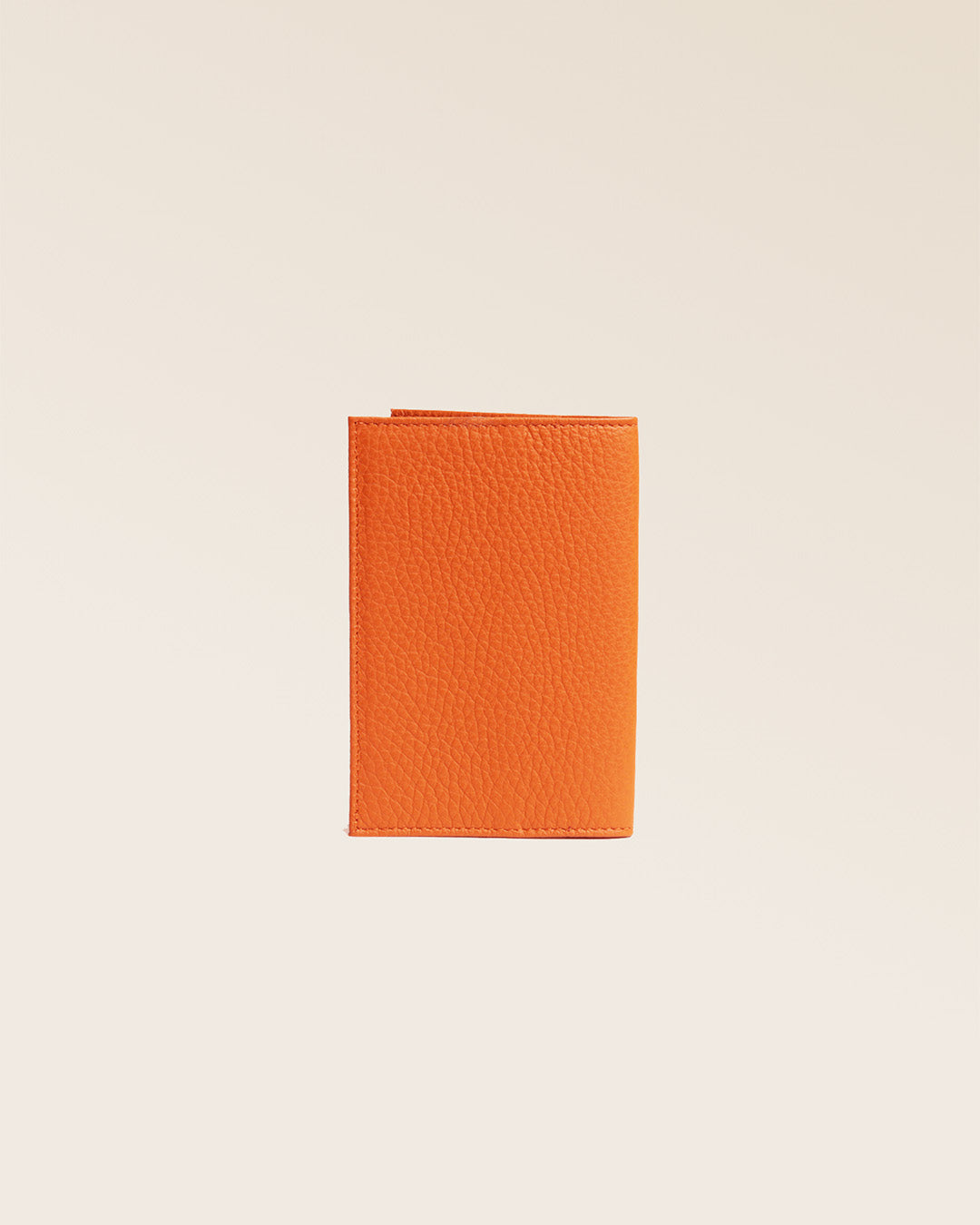 Notre étui passeport en cuir façon vigogne orange vu de dos en studio.