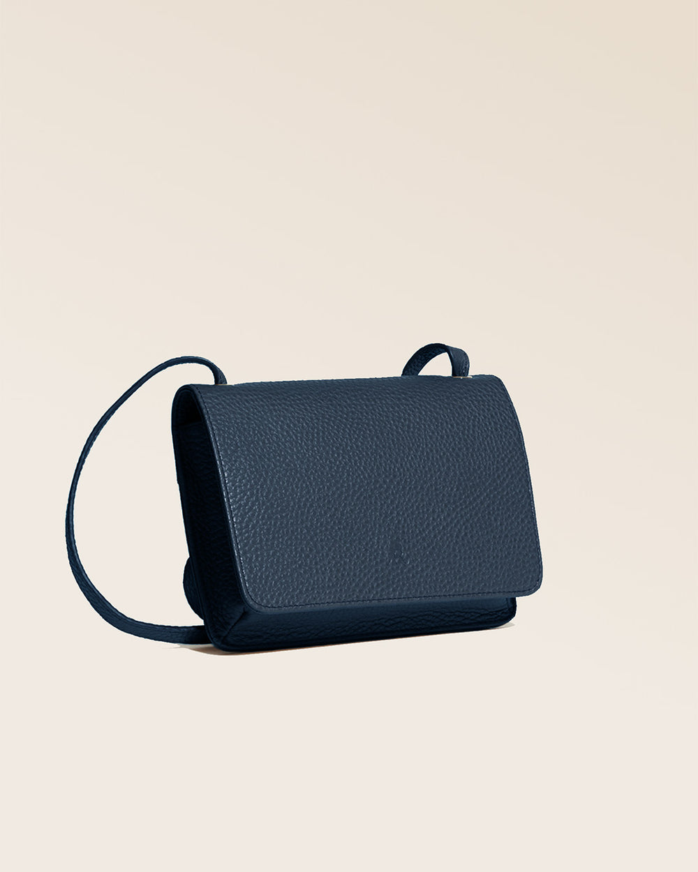 Notre pochette Frehel en cuir façon vigogne bleu marine vue de quart en studio.