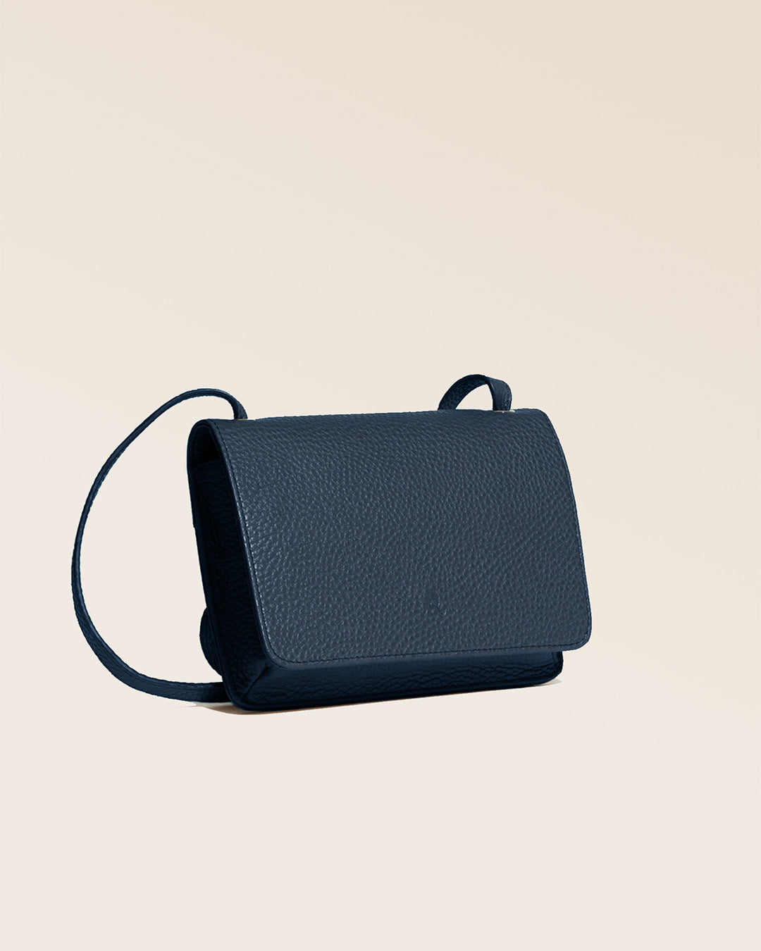 Notre pochette Frehel en cuir façon vigogne bleu marine vue de quart en studio.