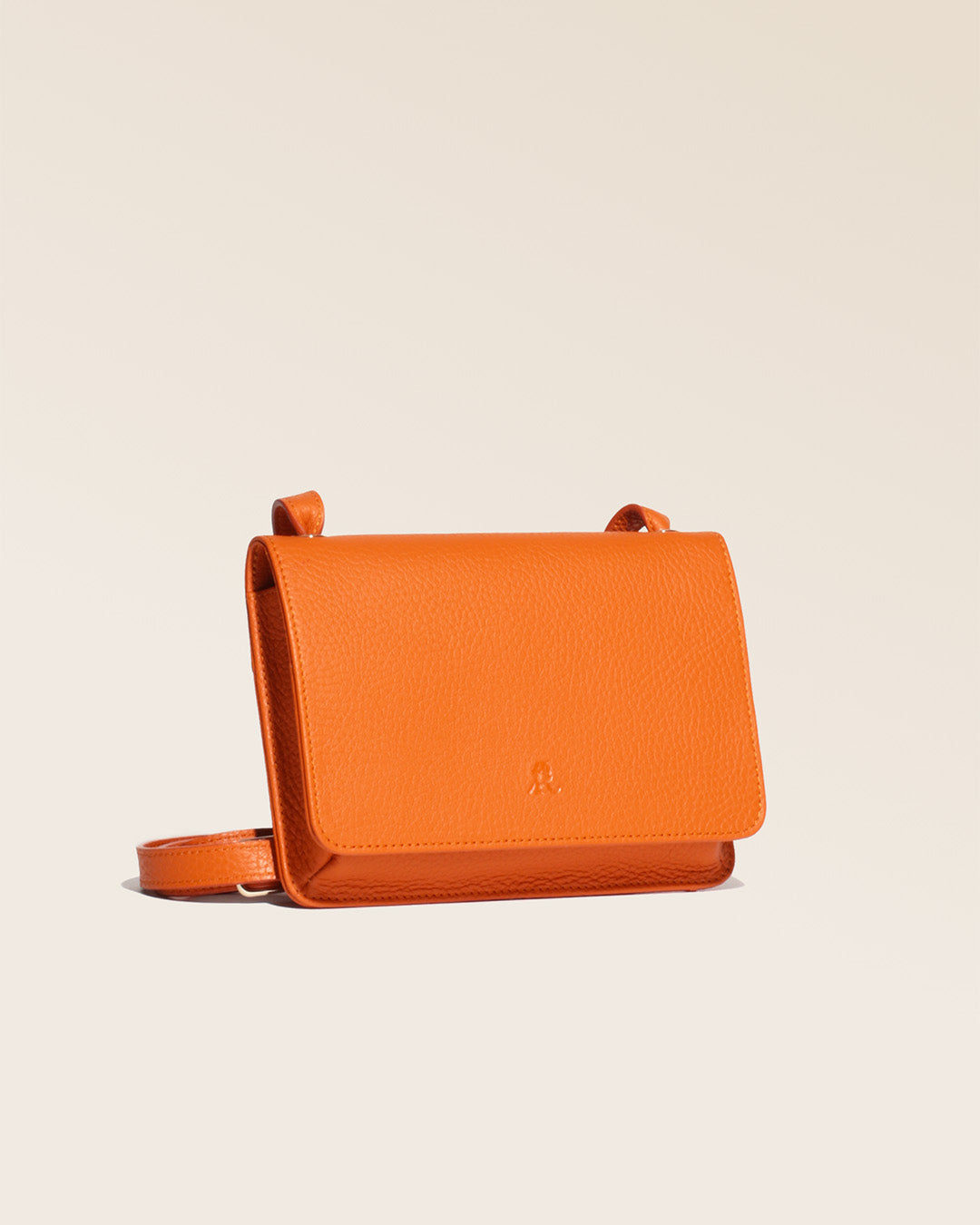Our Fréhel clutch in orange vicuña-style leather, seen from the quarter in the studio.