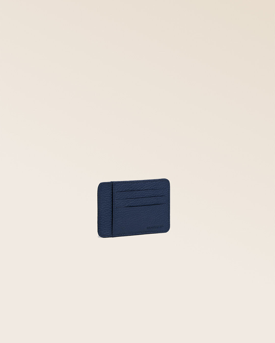 Notre porte-cartes Adam en cuir façon vigogne bleu marine vu de quart en studio.
