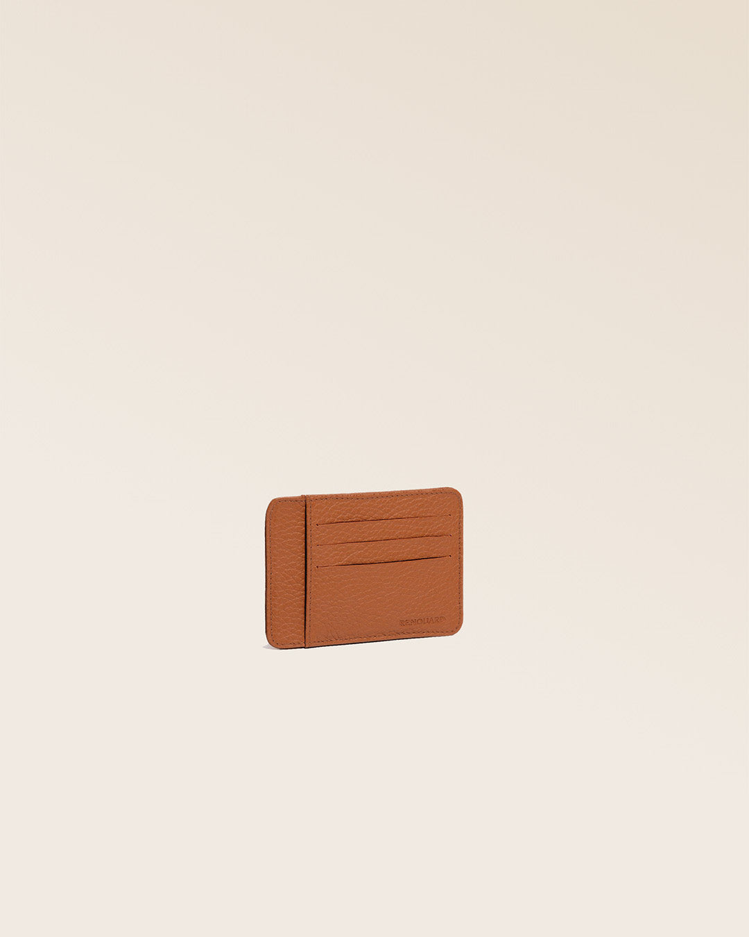 Notre porte-cartes Adam en cuir façon vigogne fauve vu de quart en studio.