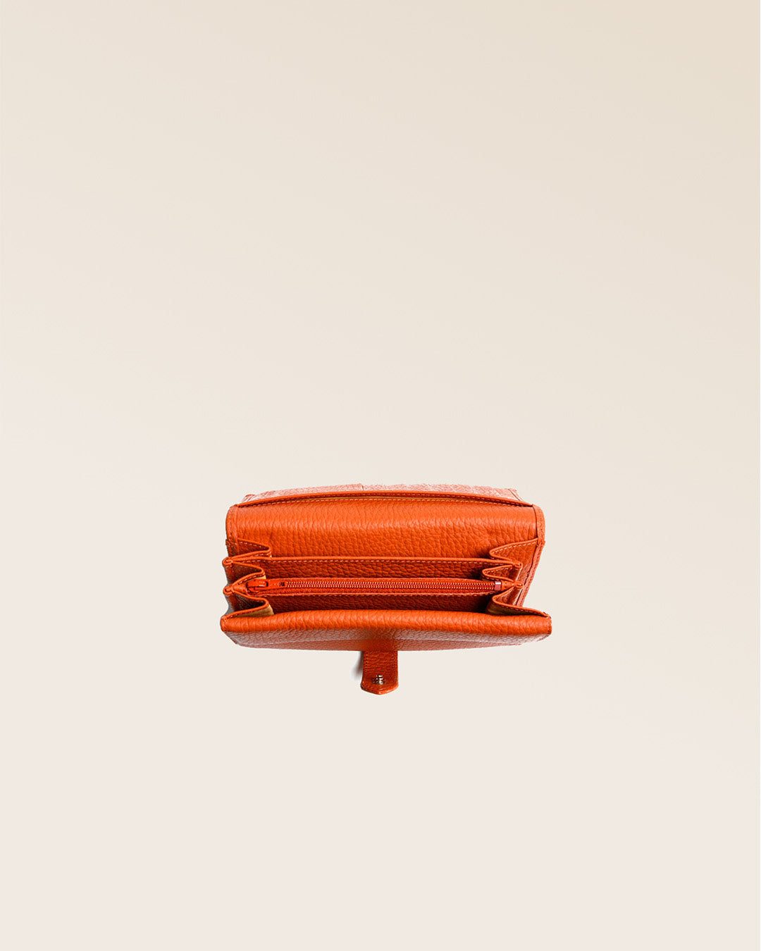 Notre porte-monnaie Adèle en cuir façon vigogne orange vu du dessus en studio.