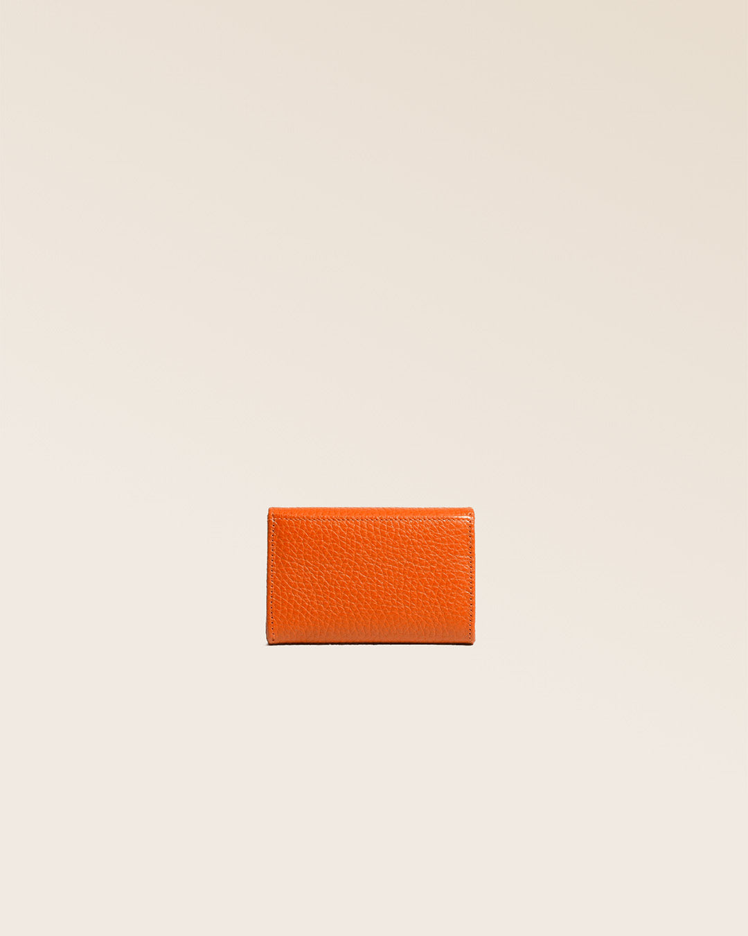 Notre porte-monnaie Alma en cuir façon vigogne orange vu de dos en studio.