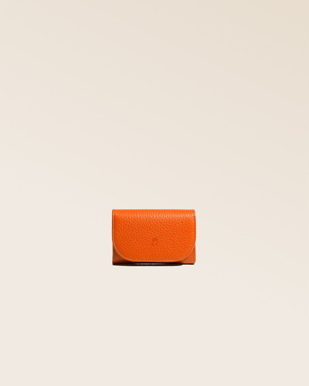 Notre porte-monnaie Alma en cuir façon vigogne orange vu de face en studio.