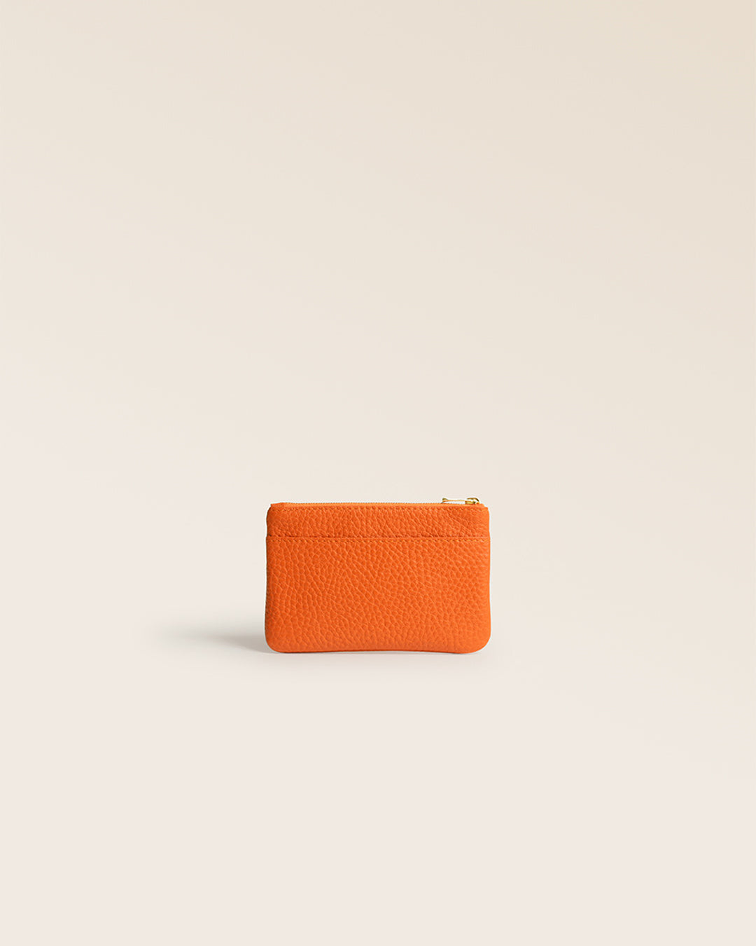 Notre porte-monnaie Capucine Renouard en cuir façon vigogne orange vu de dos en studio.
