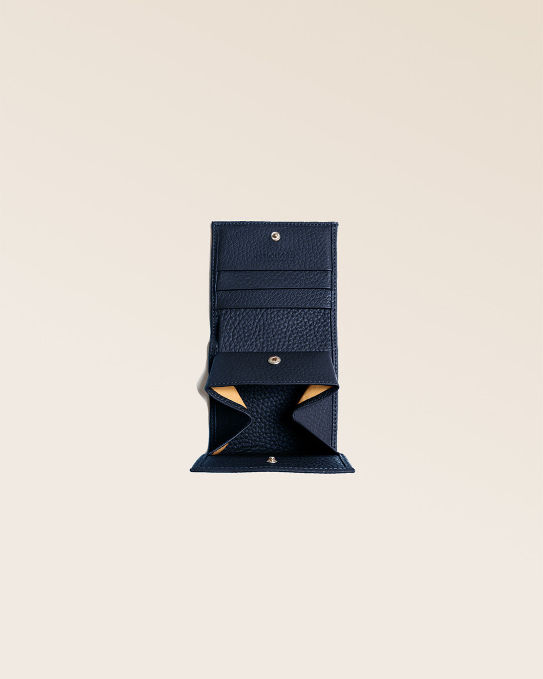 Notre porte-monnaie Castel en cuir façon vigogne bleu marine vu ouvert en studio.