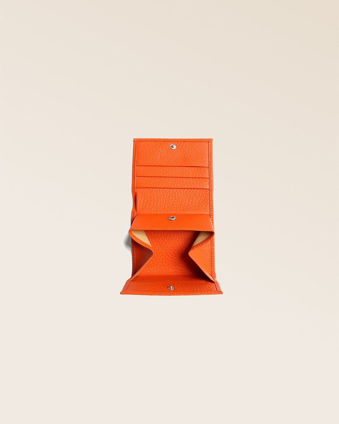 Notre porte-monnaie Castel en cuir façon vigogne orange vu ouvert en studio.