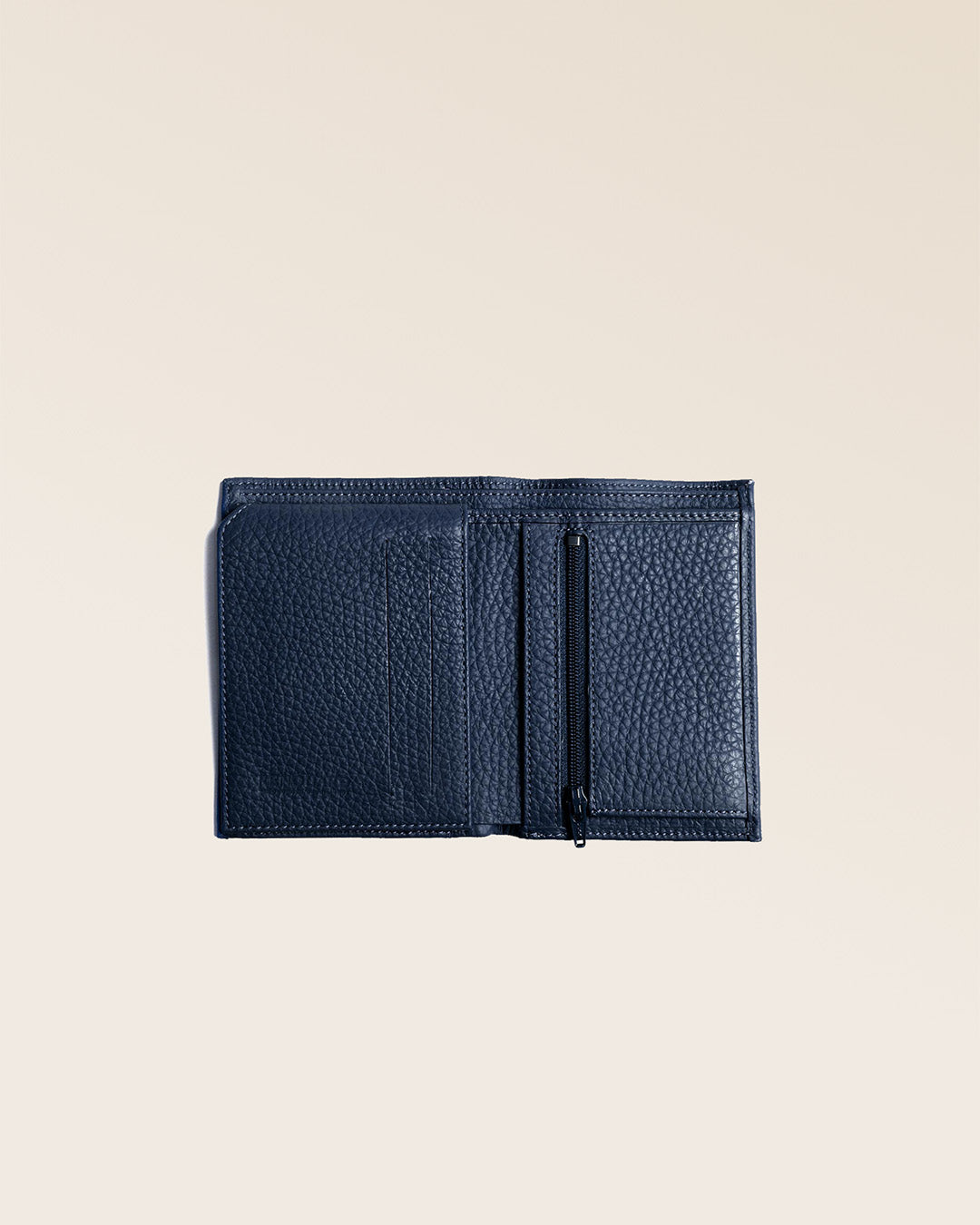 Notre portefeuile Malo en cuir façon vigogne bleu marine vu ouvert partiellement en studio.