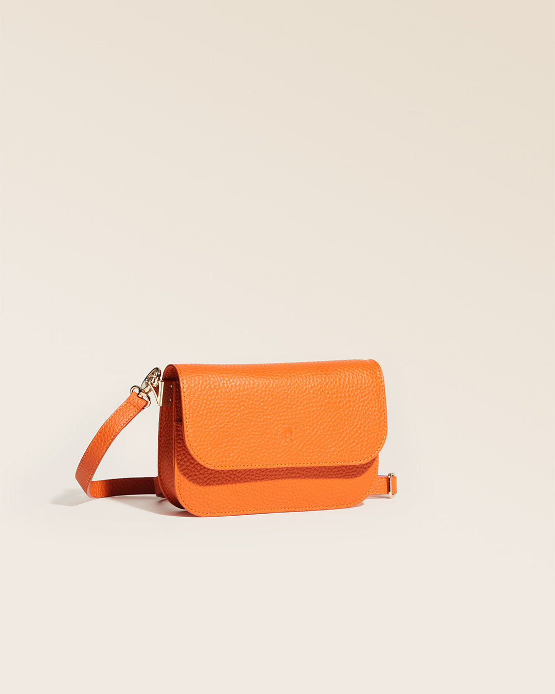 Notre pochette Coralie en cuir façon vigogne orange vue de quart en studio.
