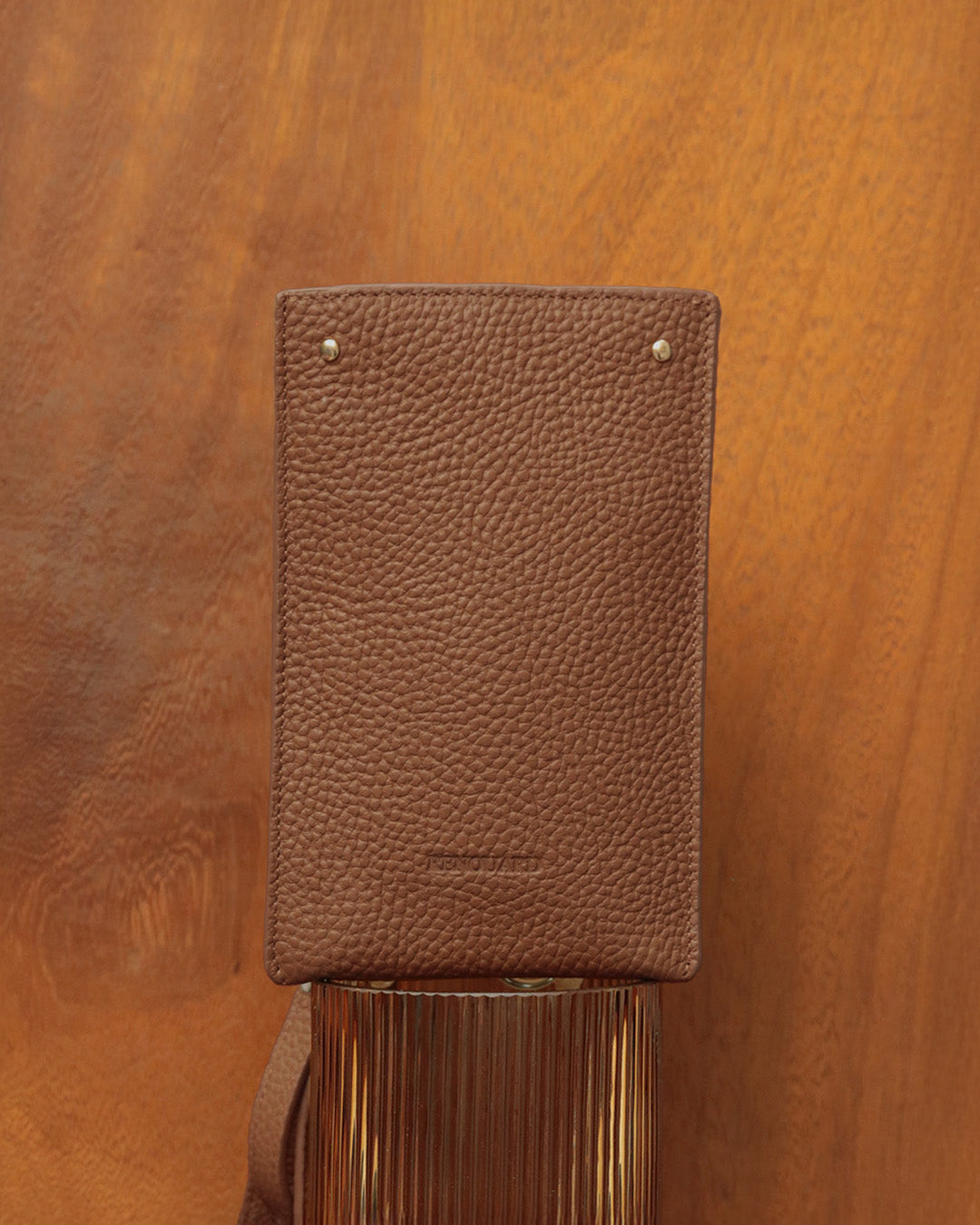 Our Renouard phone pouch in fawn-colored vicuña leather, seen from the front in ambience.