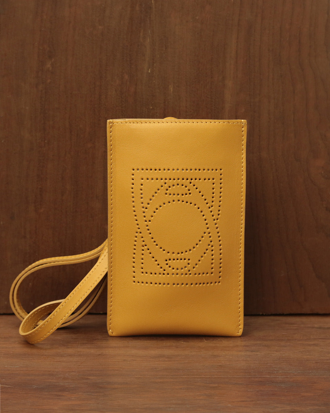 Notre pochette téléphone Étrivière Renouard en cuir lisse curry, vue de face en ambiance.