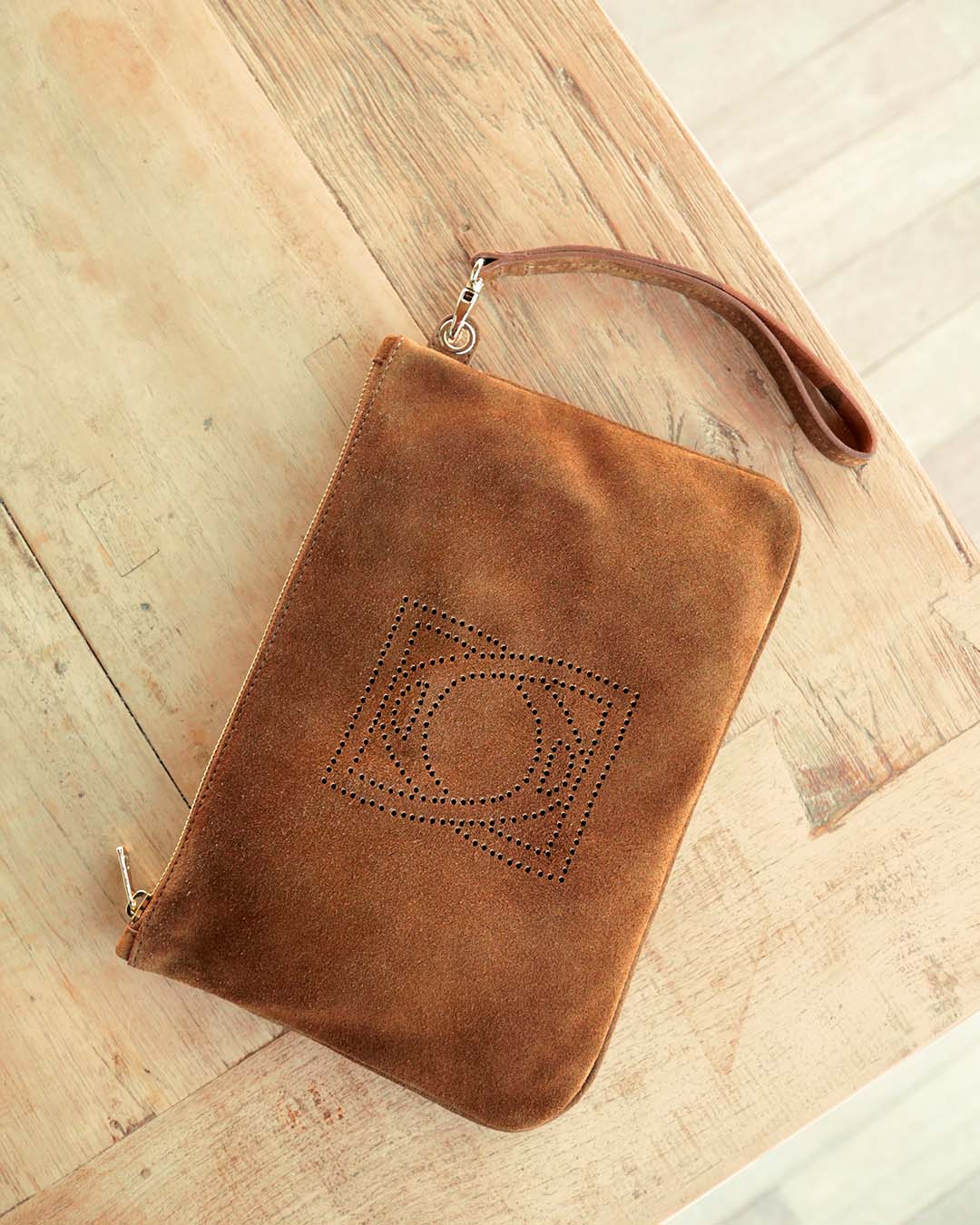 Notre pochette zippée Étrivière en cuir veau velours noisette vu de face en ambiance.