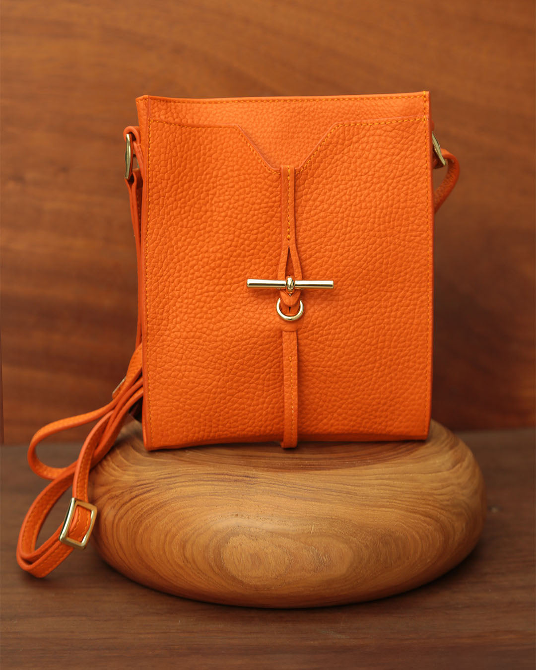 Notre pochette Aglaé Renouard en cuir façon vigogne orange, vue de face en ambiance.