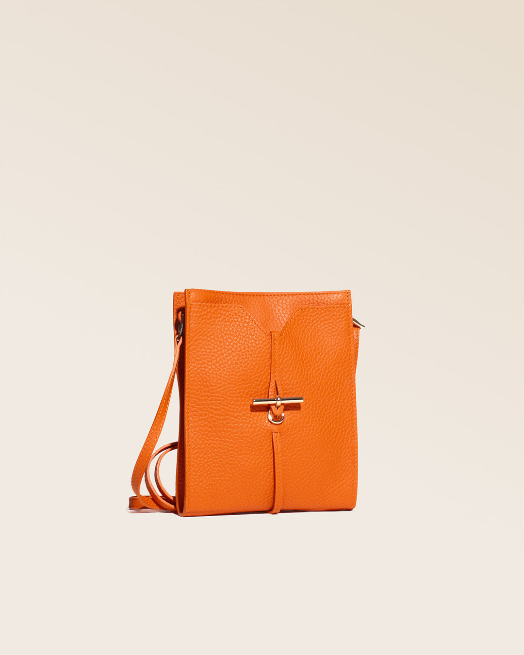 Notre pochette Aglaé Renouard en cuir façon vigogne orange, vue de quart en studio.