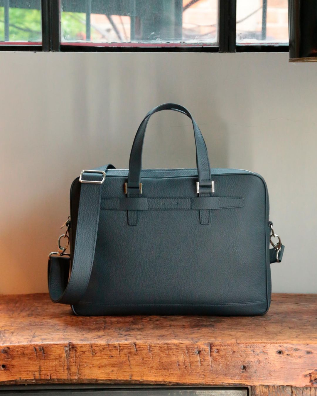 Our Boston satchel bag in navy blue vicuña-style leather, seen from the front in ambience.