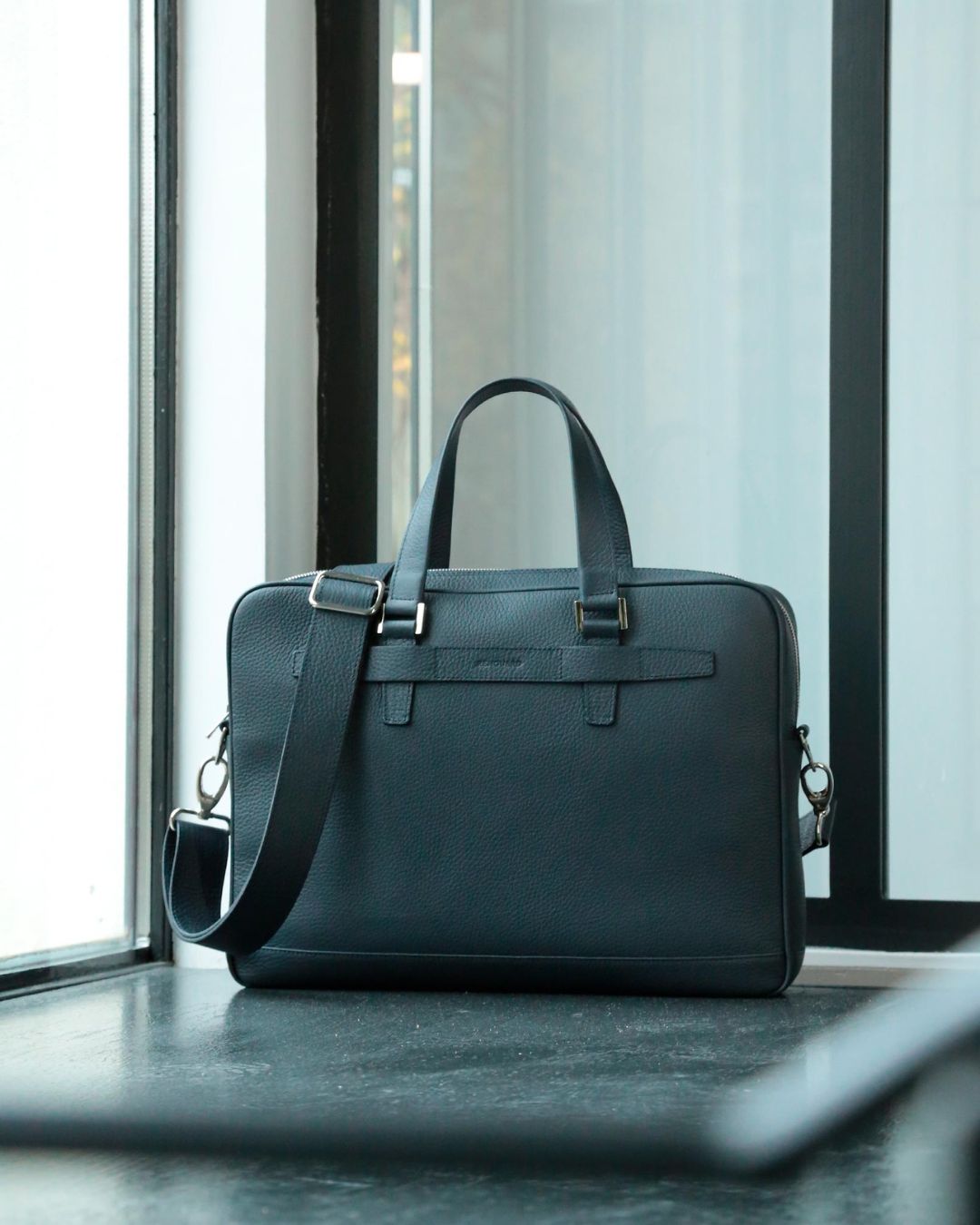 Our Boston satchel bag in navy blue vicuña-style leather, seen from the front in ambience.
