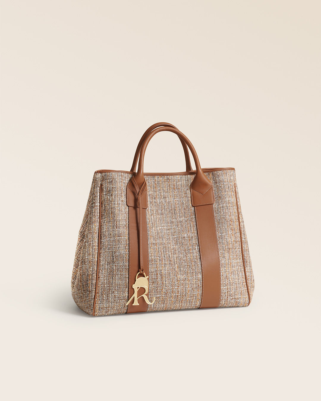 Notre sac cabas Max Renouard en toile tweed beige et cuir vintage camel, vu de quart en studio.