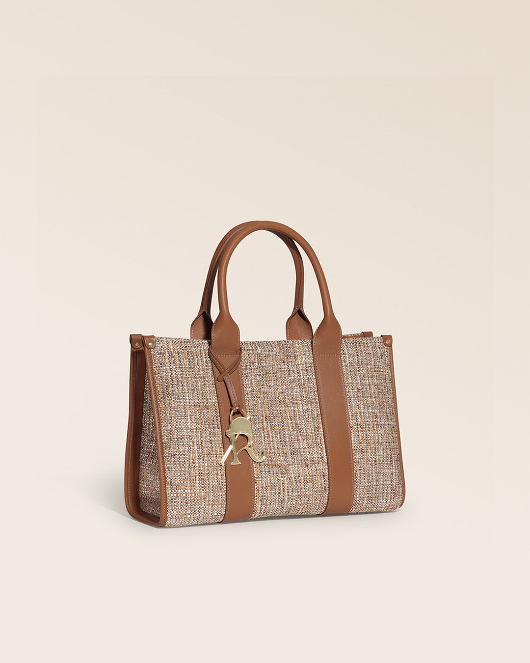 Notre sac cabas Nina Renouard en toile tweed beige et cuir vintage camel, vu de quart en studio.