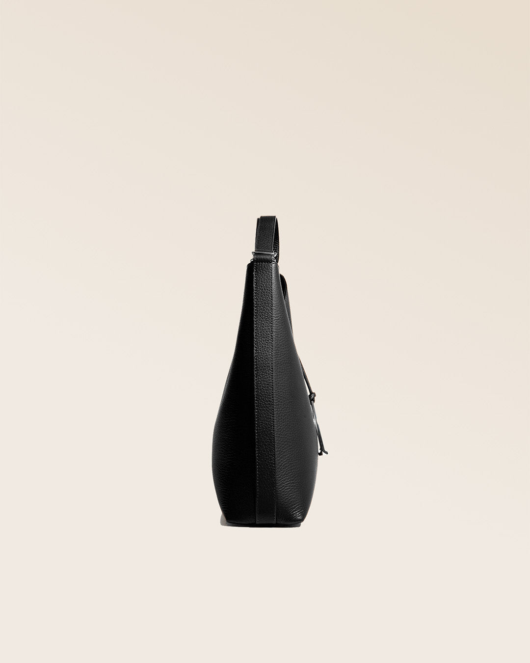 Our large Cob bag in black vicuña-style leather, seen from the side in the studio.