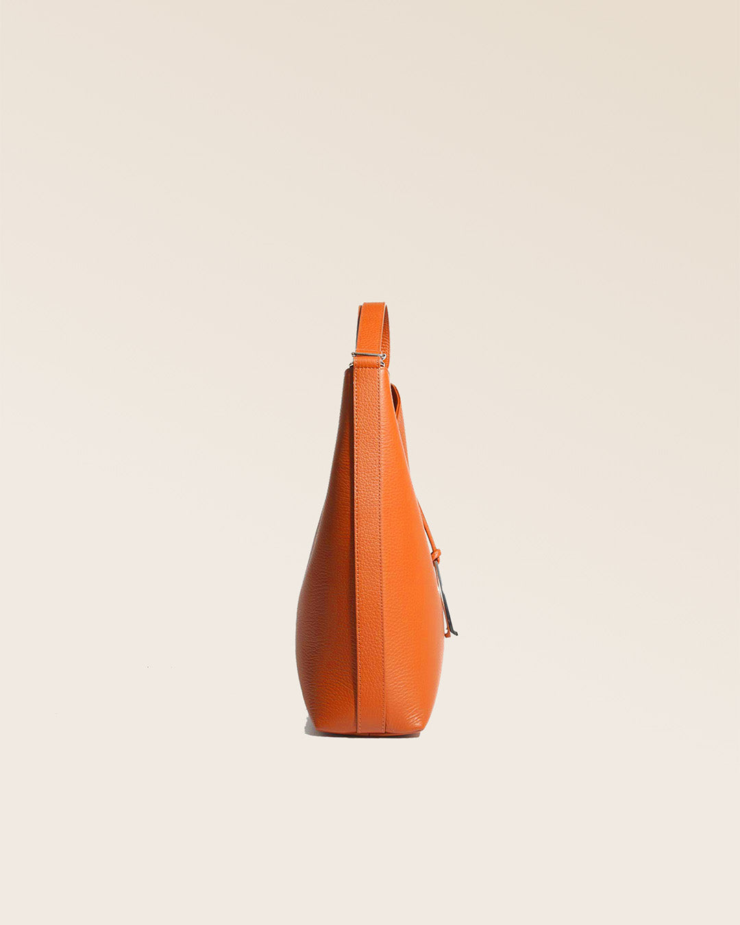 Our large Cob bag in orange vicuña-style leather, seen from the side in the studio.