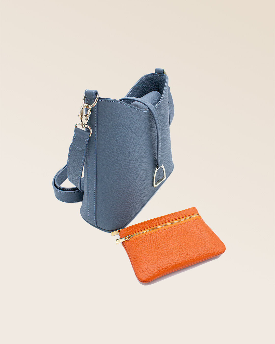 Notre sac Mini Cob en cuir façon vigogne bleu cobalt et bandoulière cuir, vu en association avec notre porte-monnaie Capucine orange, en studio.