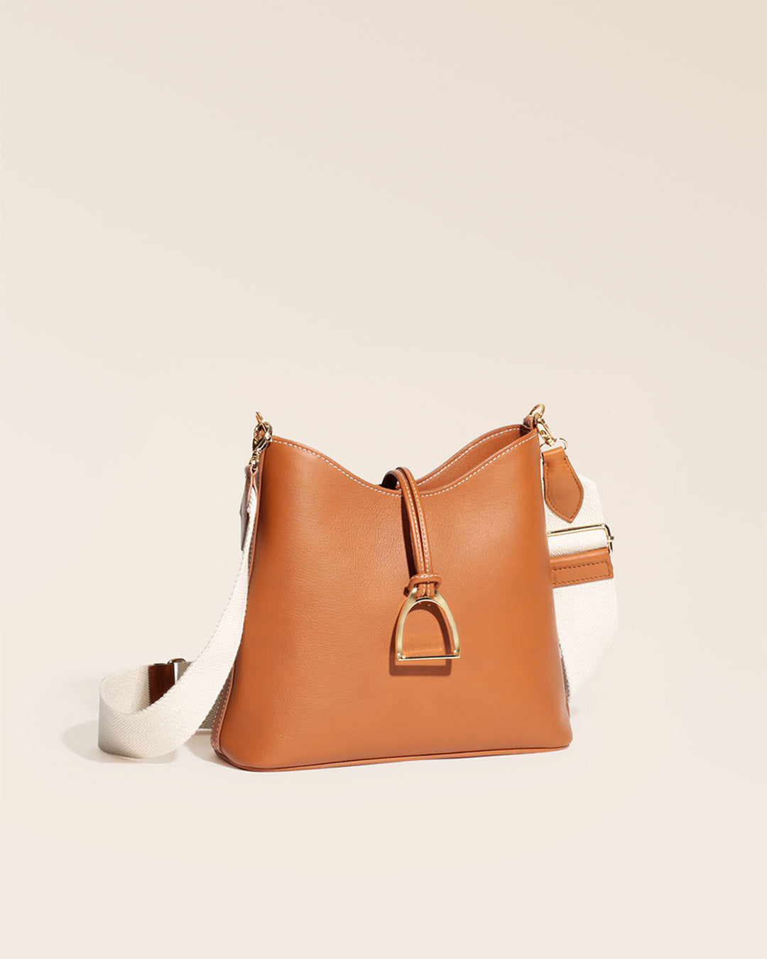 Notre sac Cob Renouard dans sa version petit modèle, cuir vintage camel et bandoulière coton, vu de quart en studio.