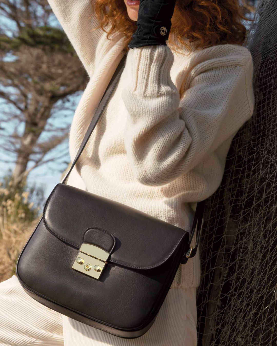 Notre sac Cornouaille en cuir lisse noir porté en bandoulière.