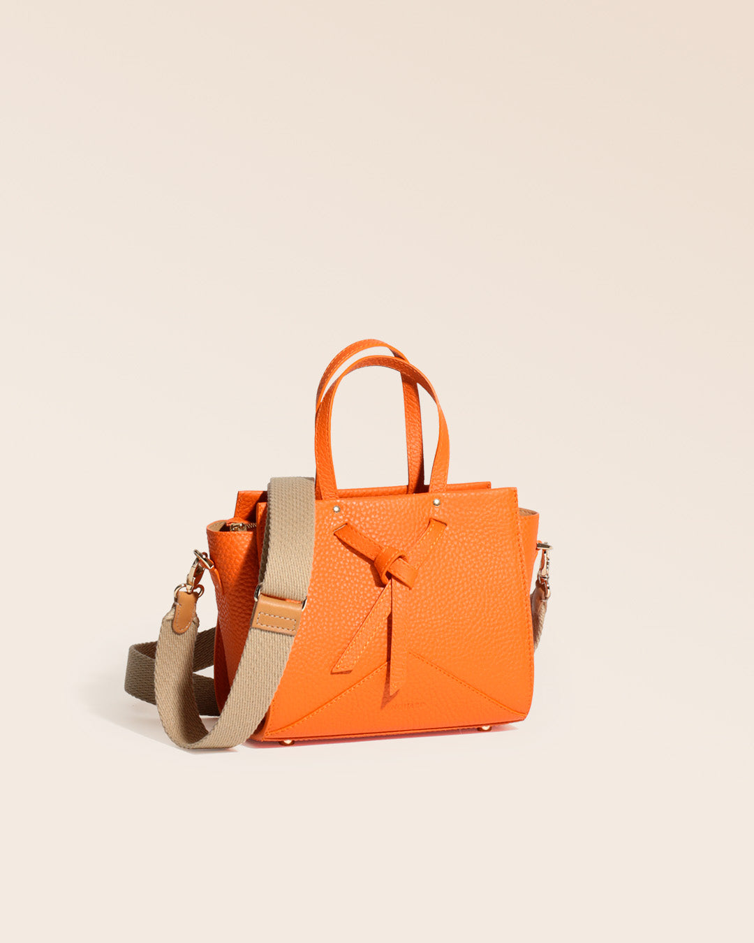 Notre sac Croisière en cuir façon vigogne orange et bandoulière coton sable, vu de quart en studio.