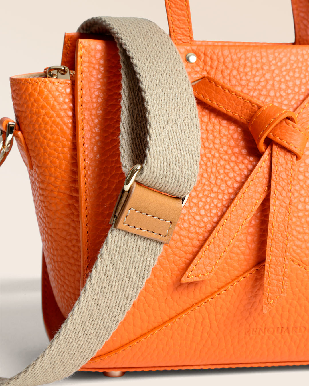 Notre sac Croisière en cuir façon vigogne orange et bandoulière coton sable, vu de près en studio.