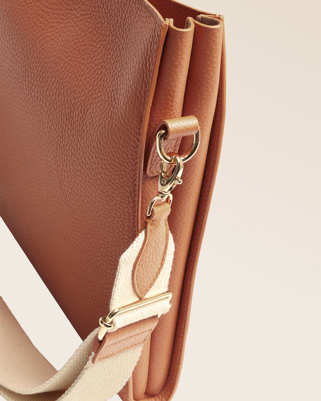 Notre sac Étrivière petit modèle en cuir façon vigogne fauve et bandoulière coton vu de près en studio.