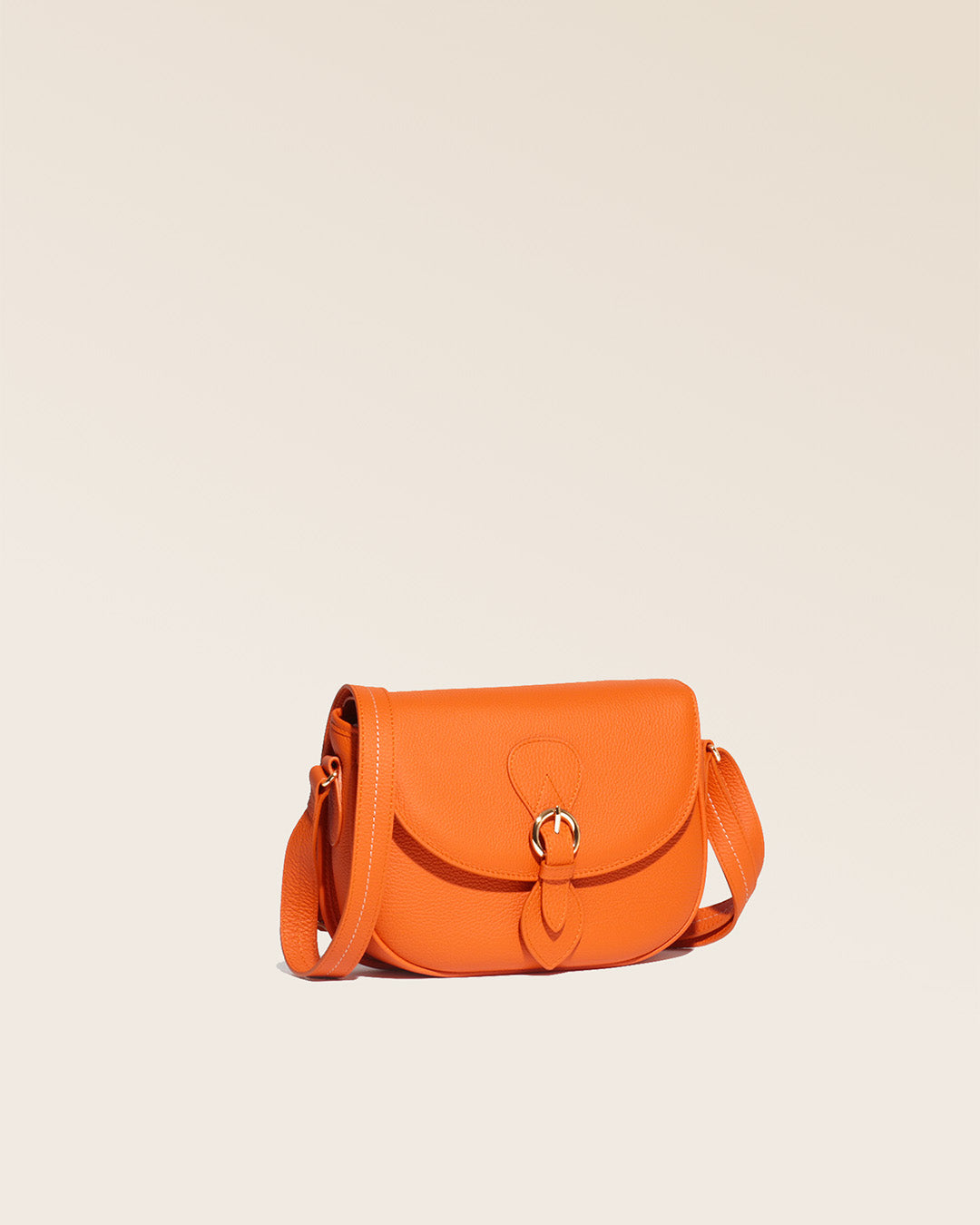 Notre sac gibecière Léa en cuir façon vigogne orange vu de quart en studio.