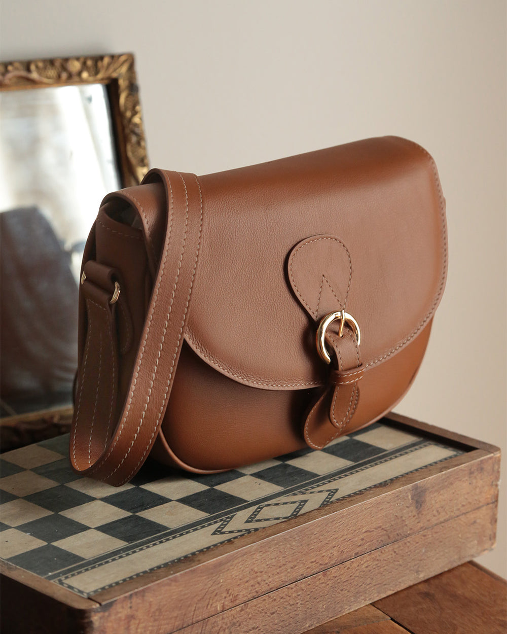 Our Léa Renouard gibecière bag in vintage camel leather, seen from the quarter in ambiance.