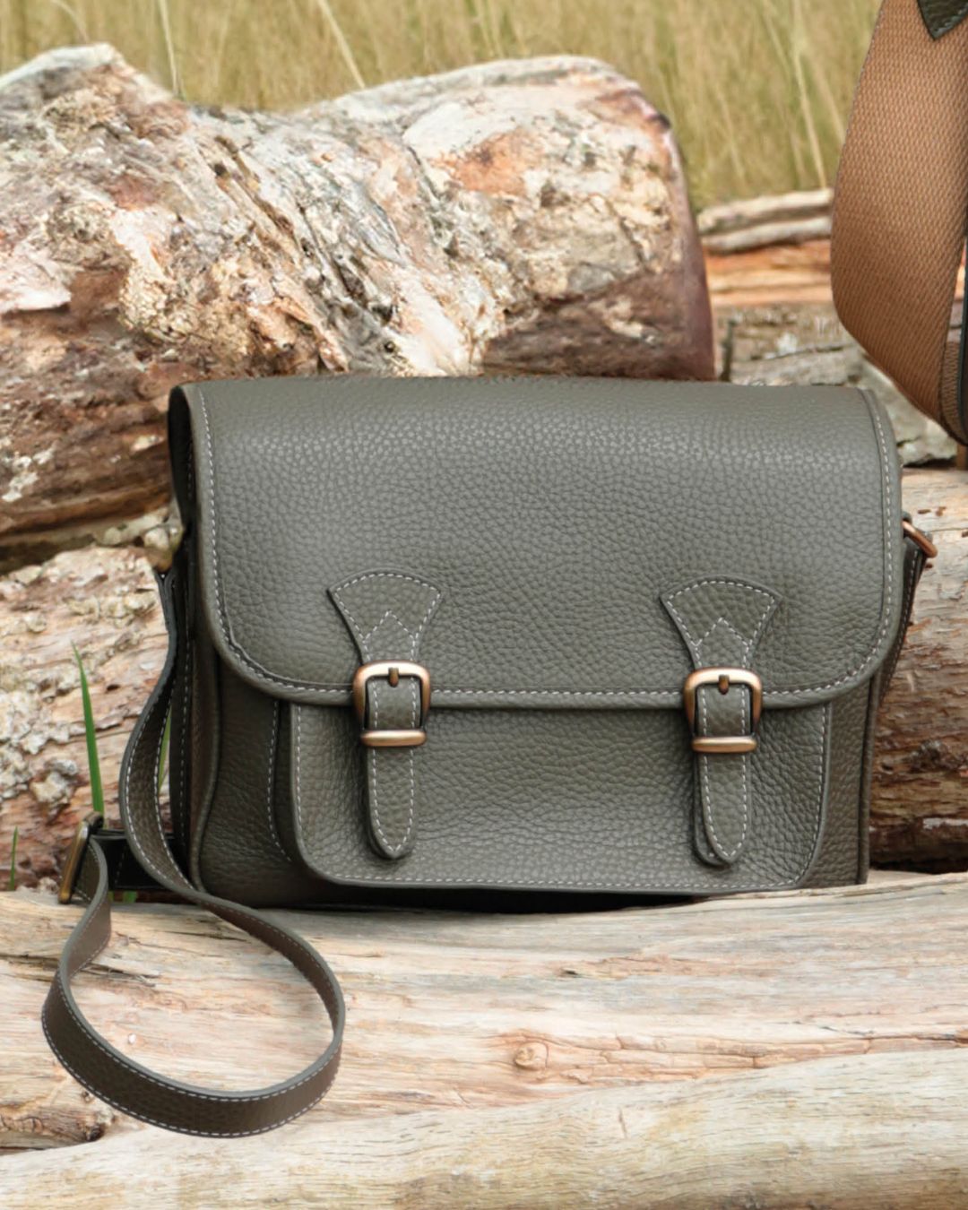 Notre sac Korrigan en cuir façon vigogne kaki vu de face, posé sur un morceau de bois.