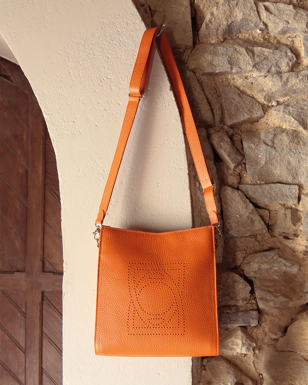 Notre sac Mini Étrivière Renouard en cuir façon vigogne orange vu en ambiance.