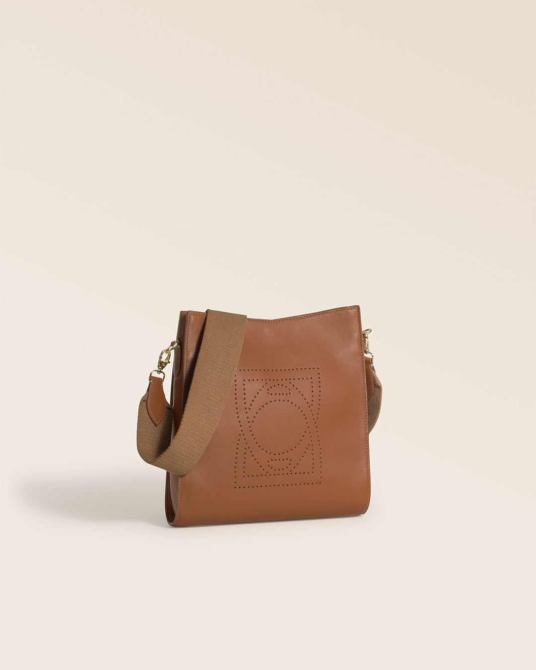 Notre sac Mini Étrivière Renouard en cuir vintage camel et bandoulière coton camel, vu de quart en studio.