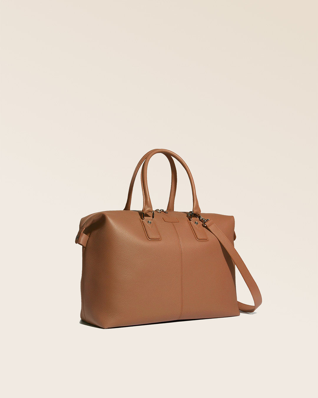 Notre sac de voyage Escapade petit modèle en cuir façon vigogne fauve vu de quart en studio.