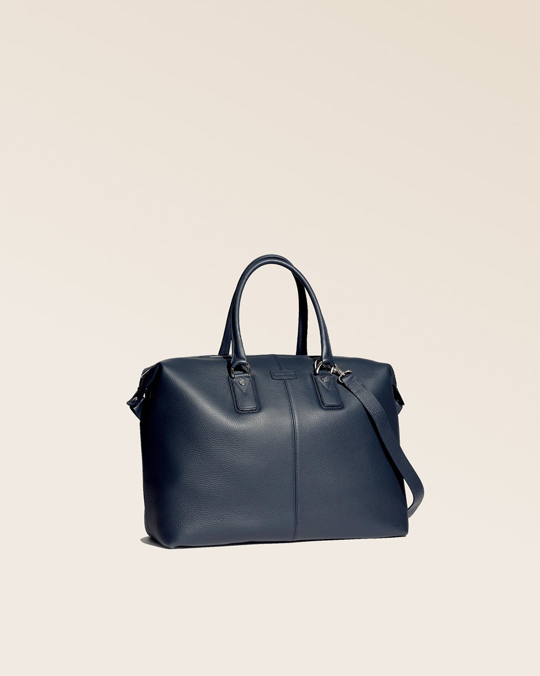 Notre sac de voyage Escapade petit modèle en cuir façon vigogne bleu marine vu de quart en studio.
